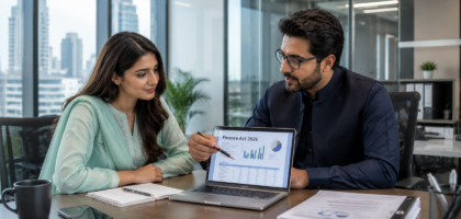 Pakistani tax consultant and female entrepreneur discussing Finance Act 2026 Pakistan in a modern office with laptop showing tax charts.