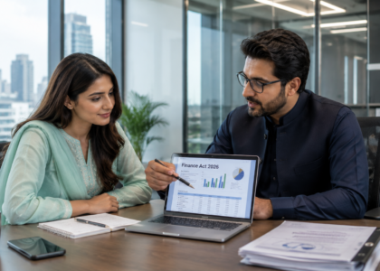 Pakistani tax consultant and female entrepreneur discussing Finance Act 2026 Pakistan in a modern office with laptop showing tax charts.